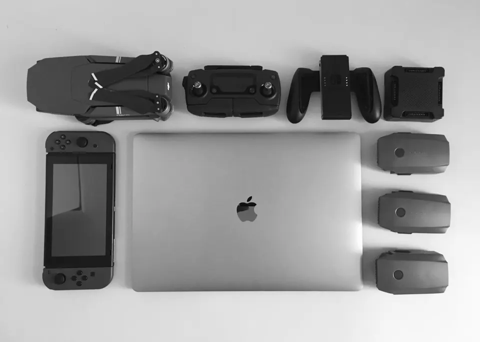 MacBook đặt cạnh máy chơi game cầm tay, flycam và nhiều thiết bị công nghệ