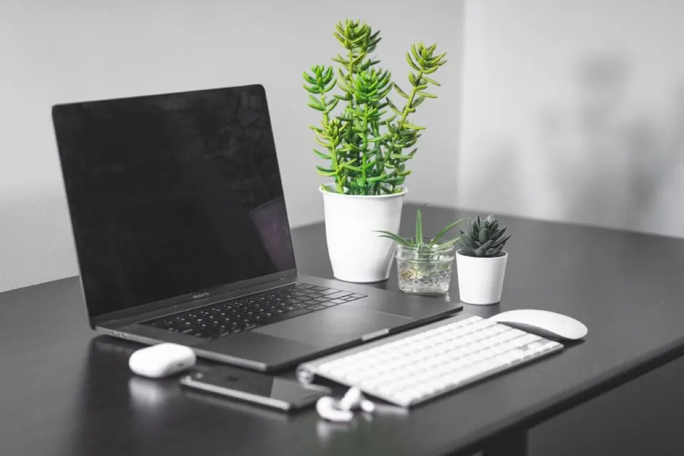 MacBook bên cạnh bàn phím và chuột không dây trên bàn làm việc gọn gàng