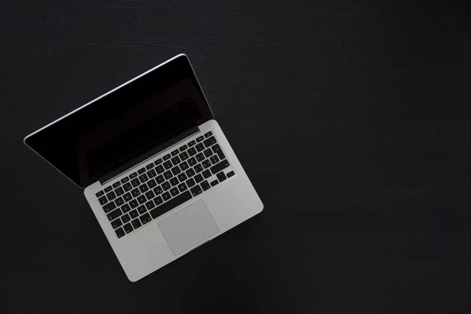 MacBook đặt trên bàn làm việc tối màu nhìn từ trên xuống