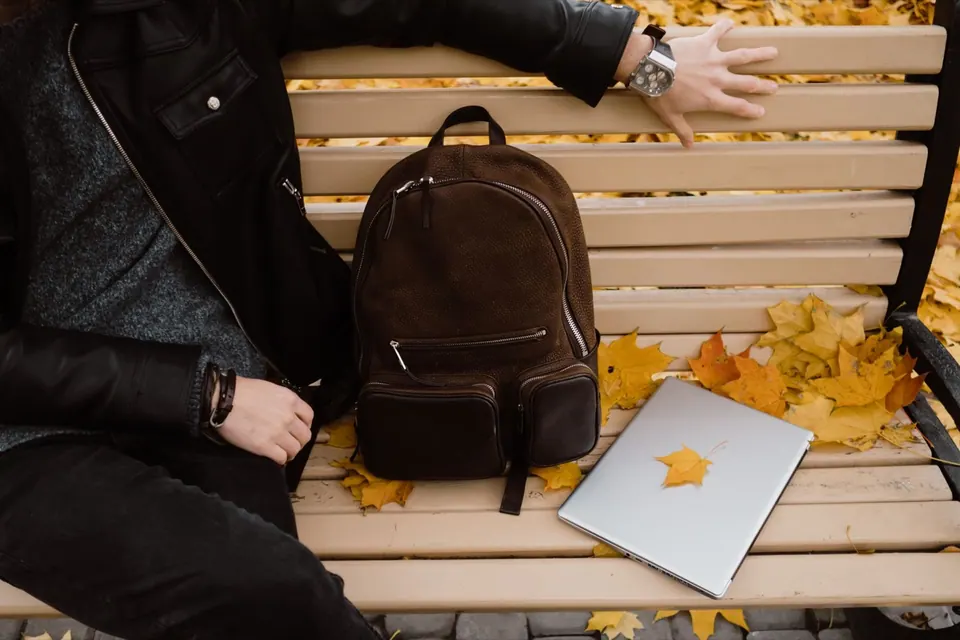 Balo da đặt cạnh MacBook trên ghế công viên