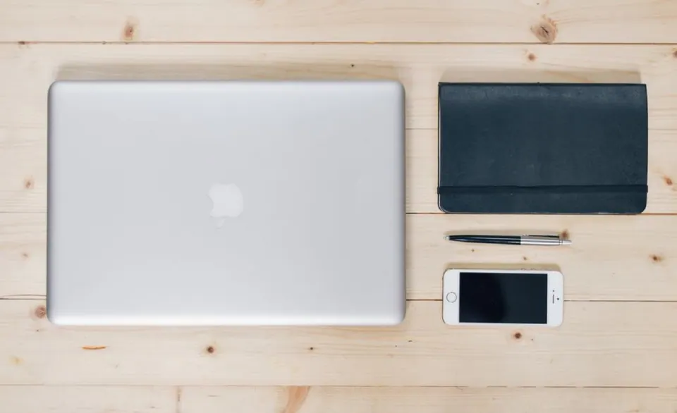 MacBook nhìn từ trên xuống cạnh ví và điện thoại